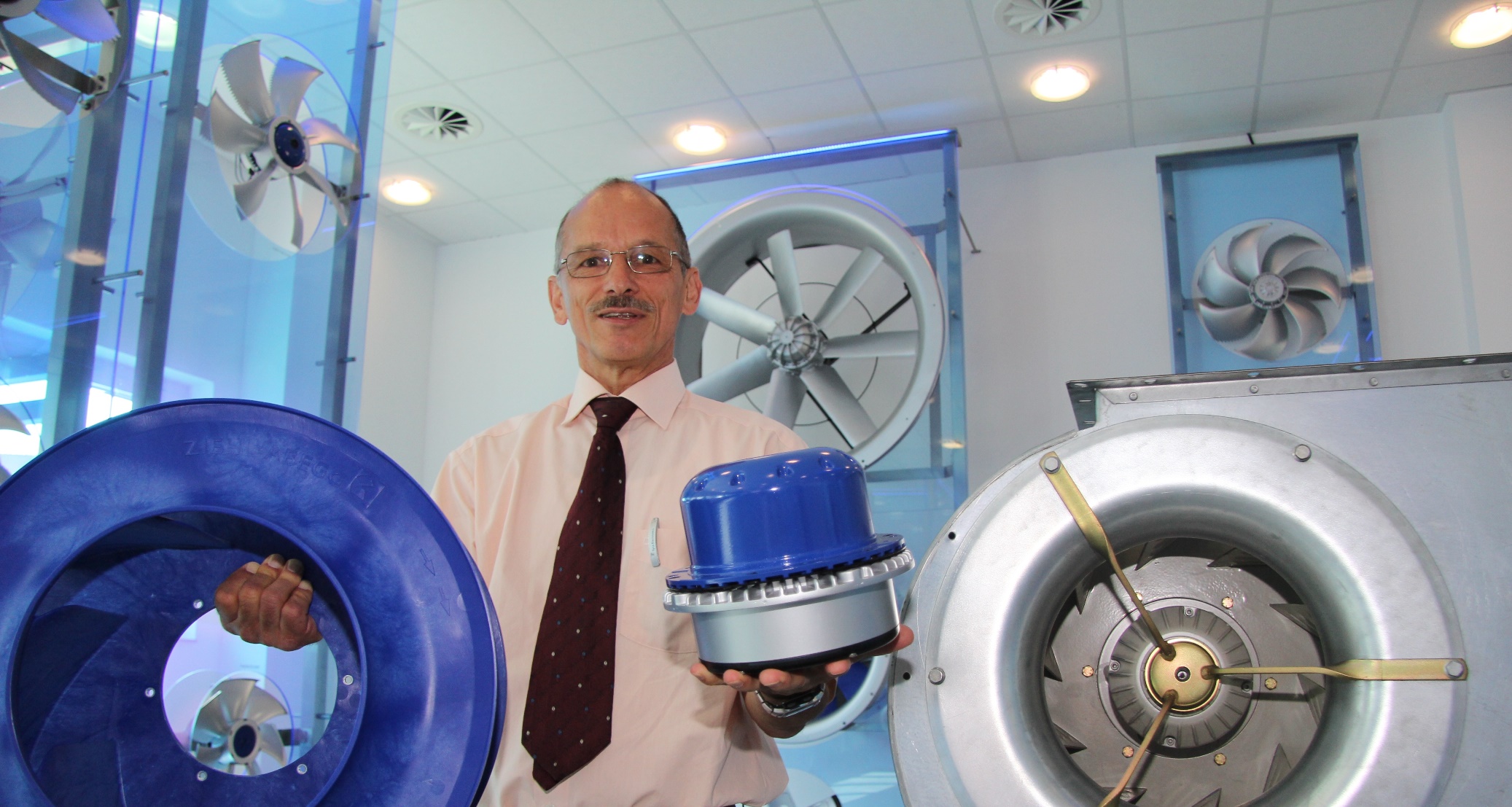 Gerhard Leutwein, a capo del settore  Electronics Development presso Ziehl-Abegg, presenta un vecchio sistema  (a destra) con a fianco la tecnologia attuale un moderno motore EC con ventilatore Cpro in materiale plastico  altamente performante 
